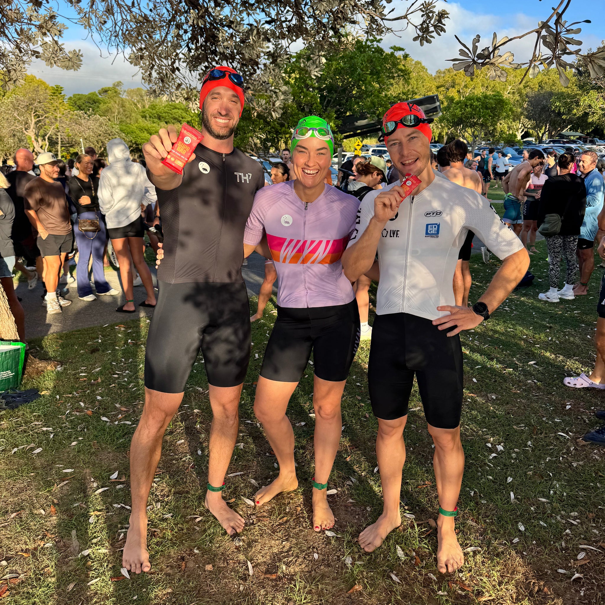 Group of people in athletic gear standing on grass with trees in the background