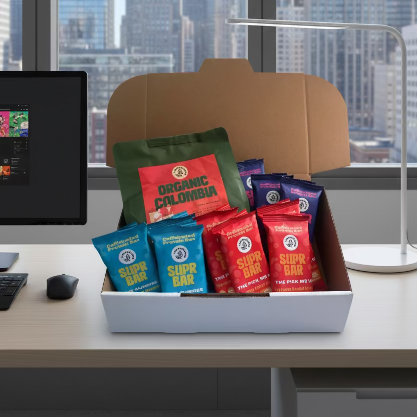 Box of coffee packages including 'Super Bar' and 'Organic Colombia' on a light surface.